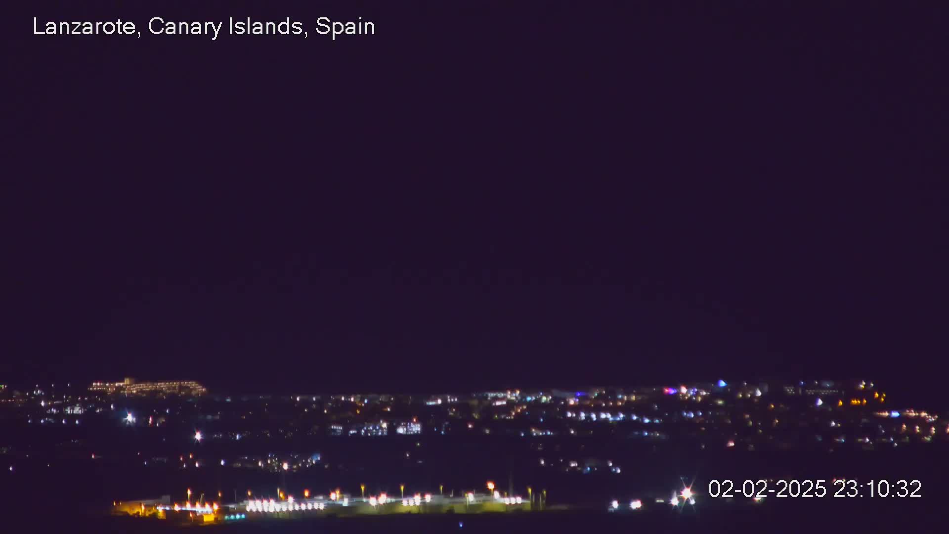 A nighttime view of a city illuminated by scattered lights under a clear, dark sky.