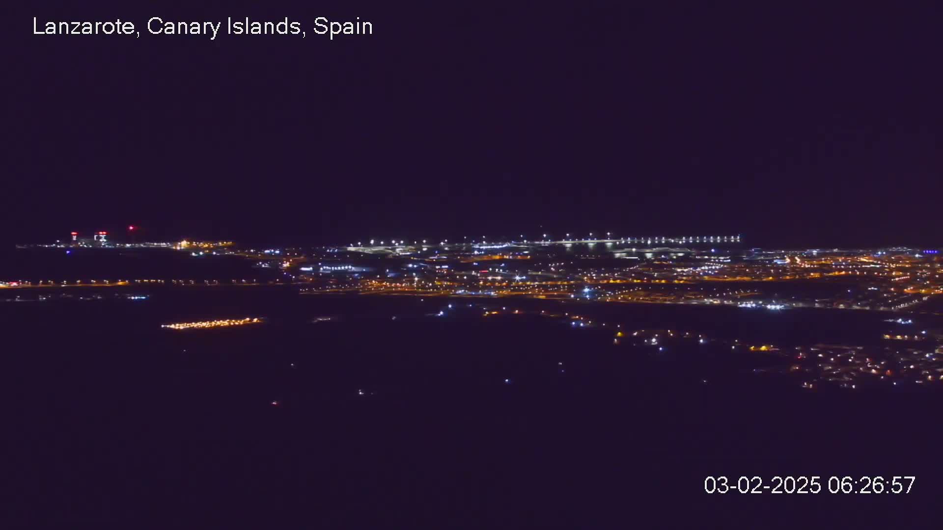 A nighttime, long-range view shows a city illuminated by many small lights against a dark sky.