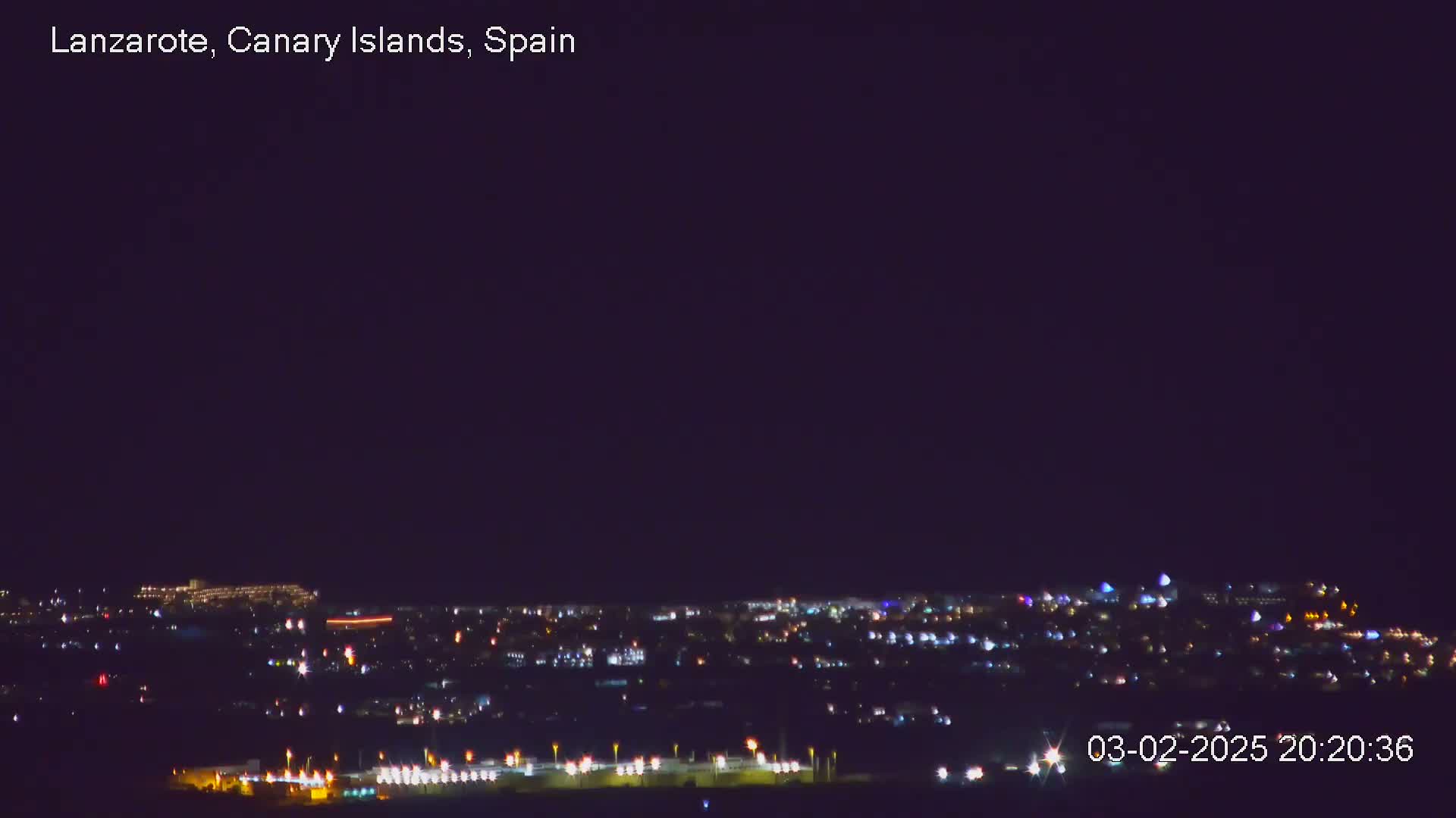A nighttime view of a city illuminated by many small lights under a dark, clear sky.