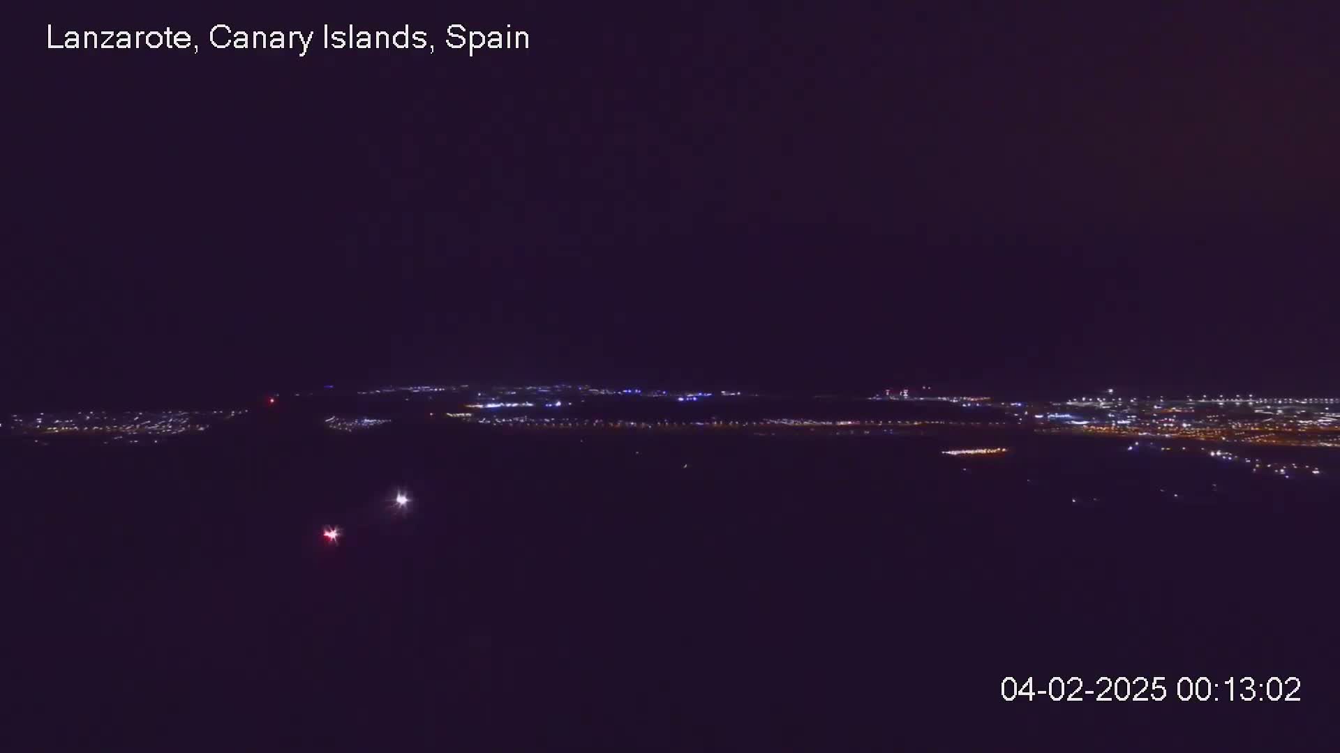 A nighttime, long-range view of a city's lights spread across a dark landscape.
