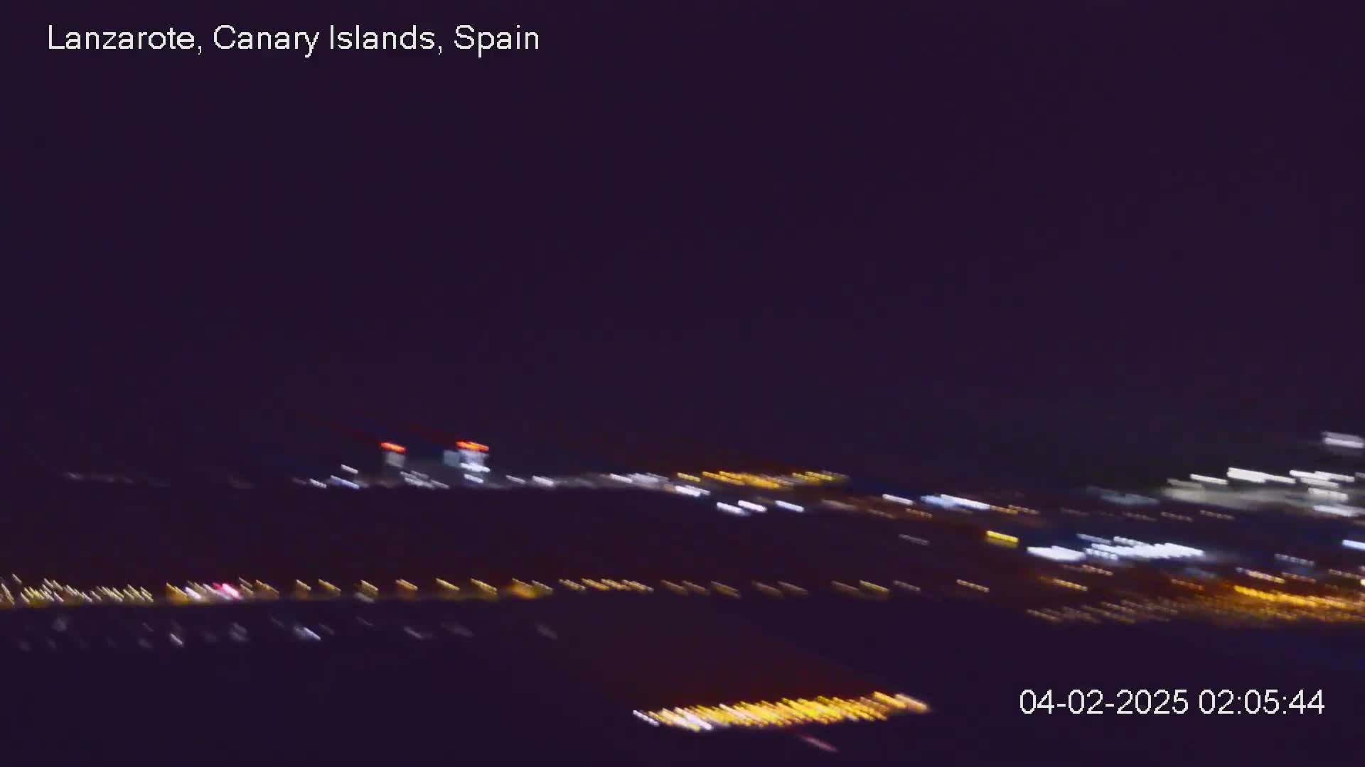 A blurry nighttime view of city lights stretches across the horizon under a dark sky.