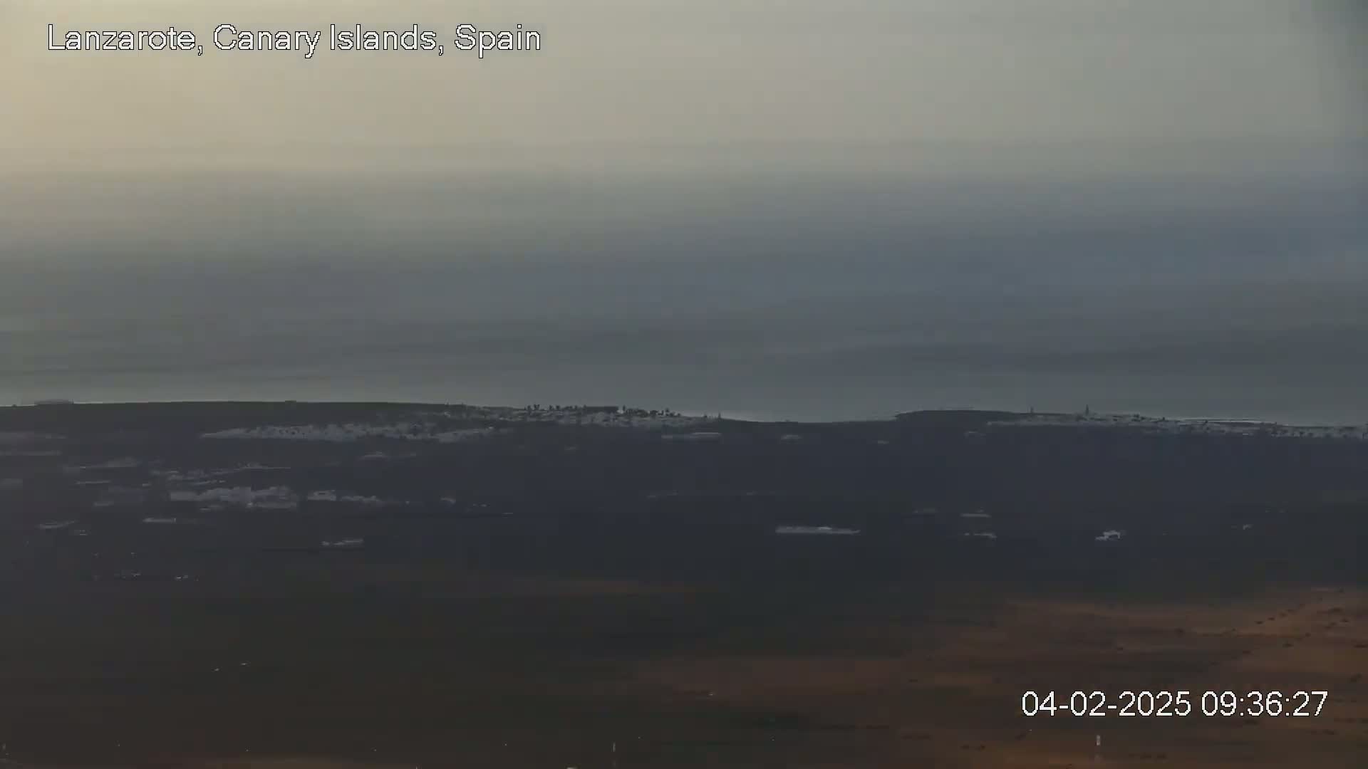 A distant coastal town is visible under an overcast sky.
