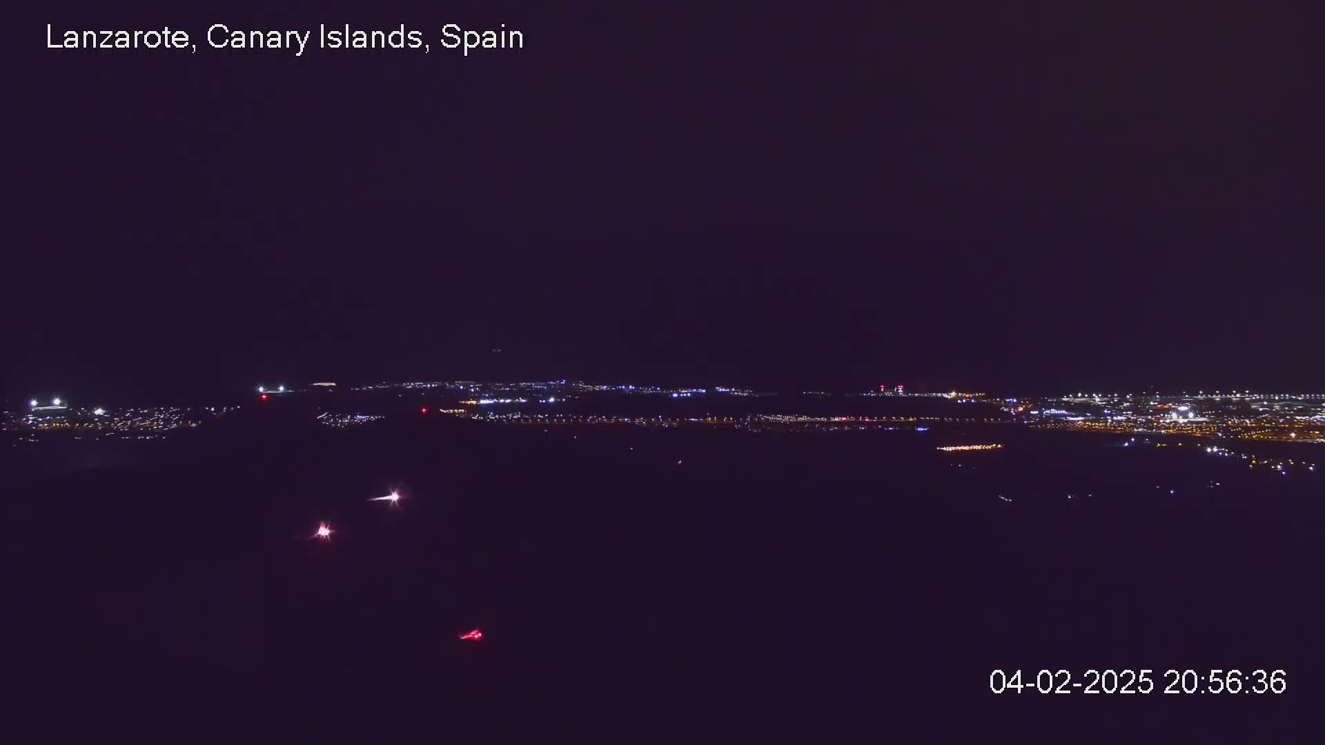 A nighttime, long-distance view of a city illuminated by lights against a dark sky.