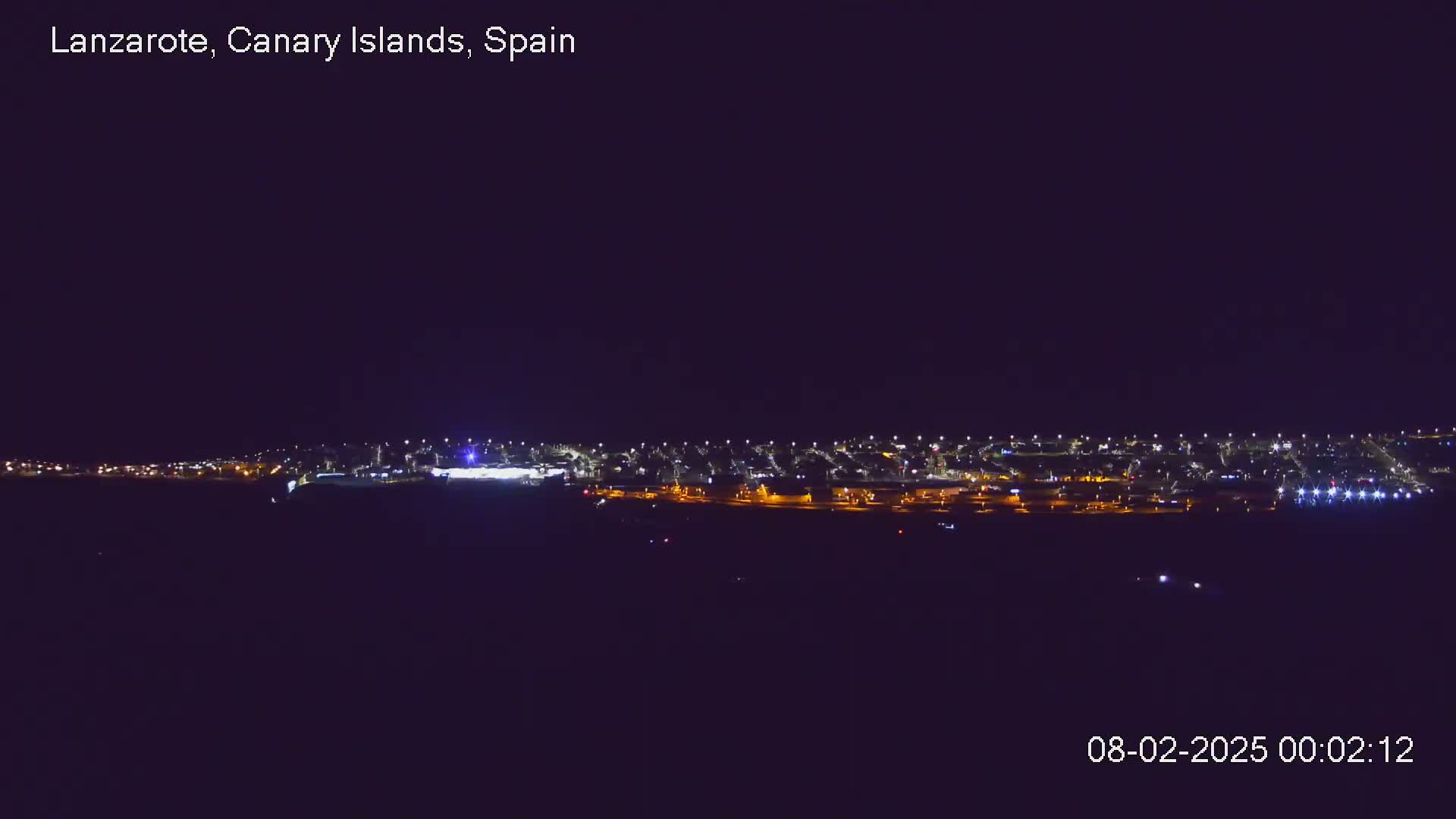 A long line of lights from a town or city is visible at night under a clear, dark sky.
