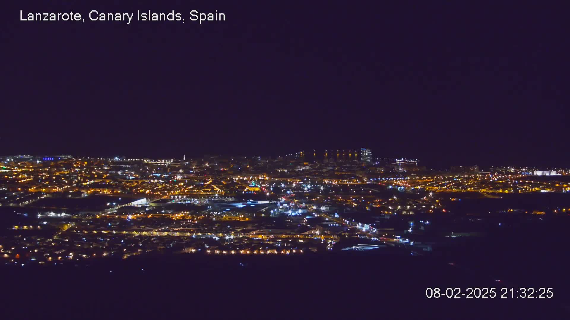 A nighttime, aerial view of a city illuminated by numerous lights under a clear, dark sky.