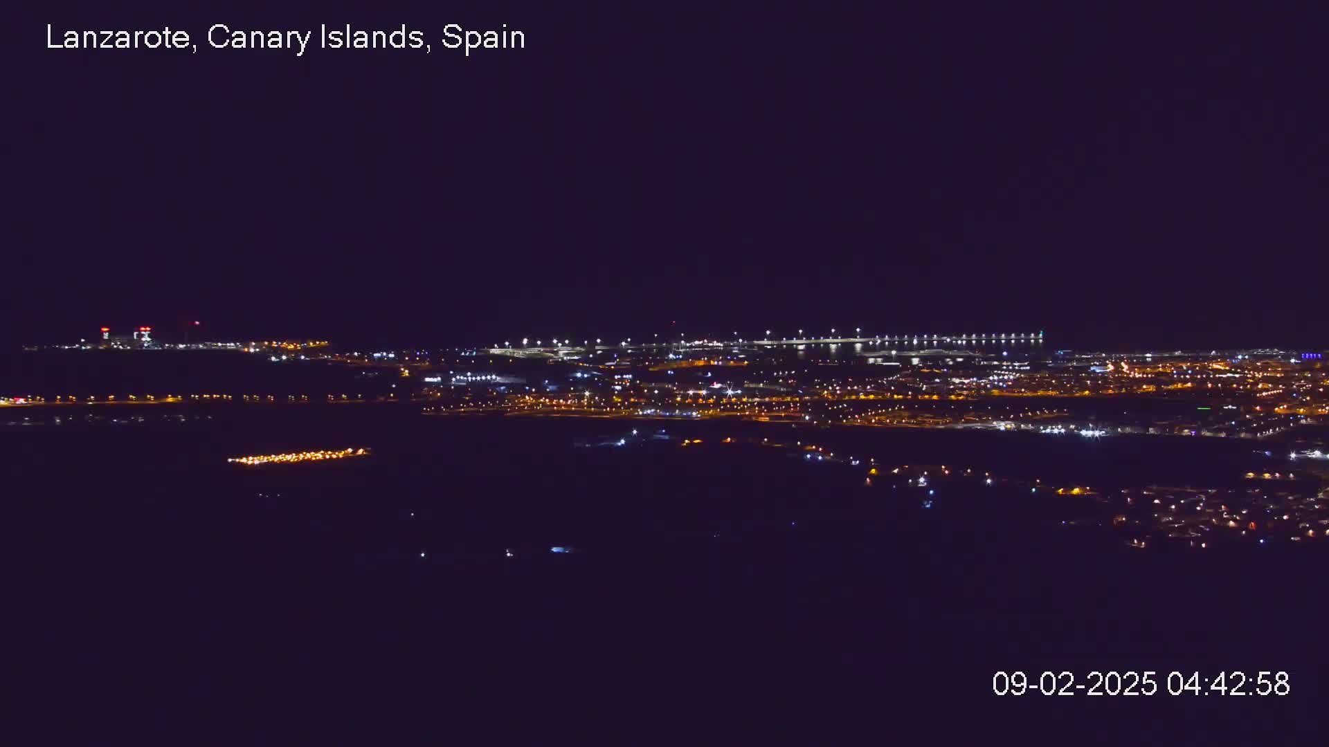 A nighttime, long-range view of a city illuminated by lights, under a clear, dark sky.