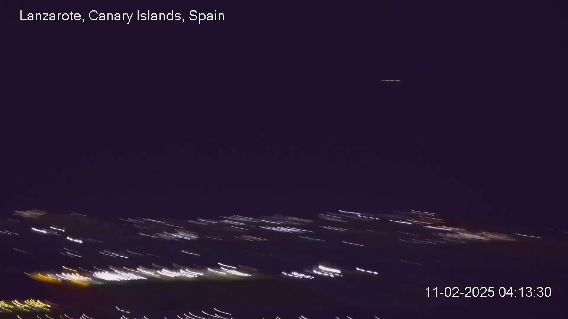 A nighttime long-exposure shot shows streaks of light from moving vehicles below a dark sky.