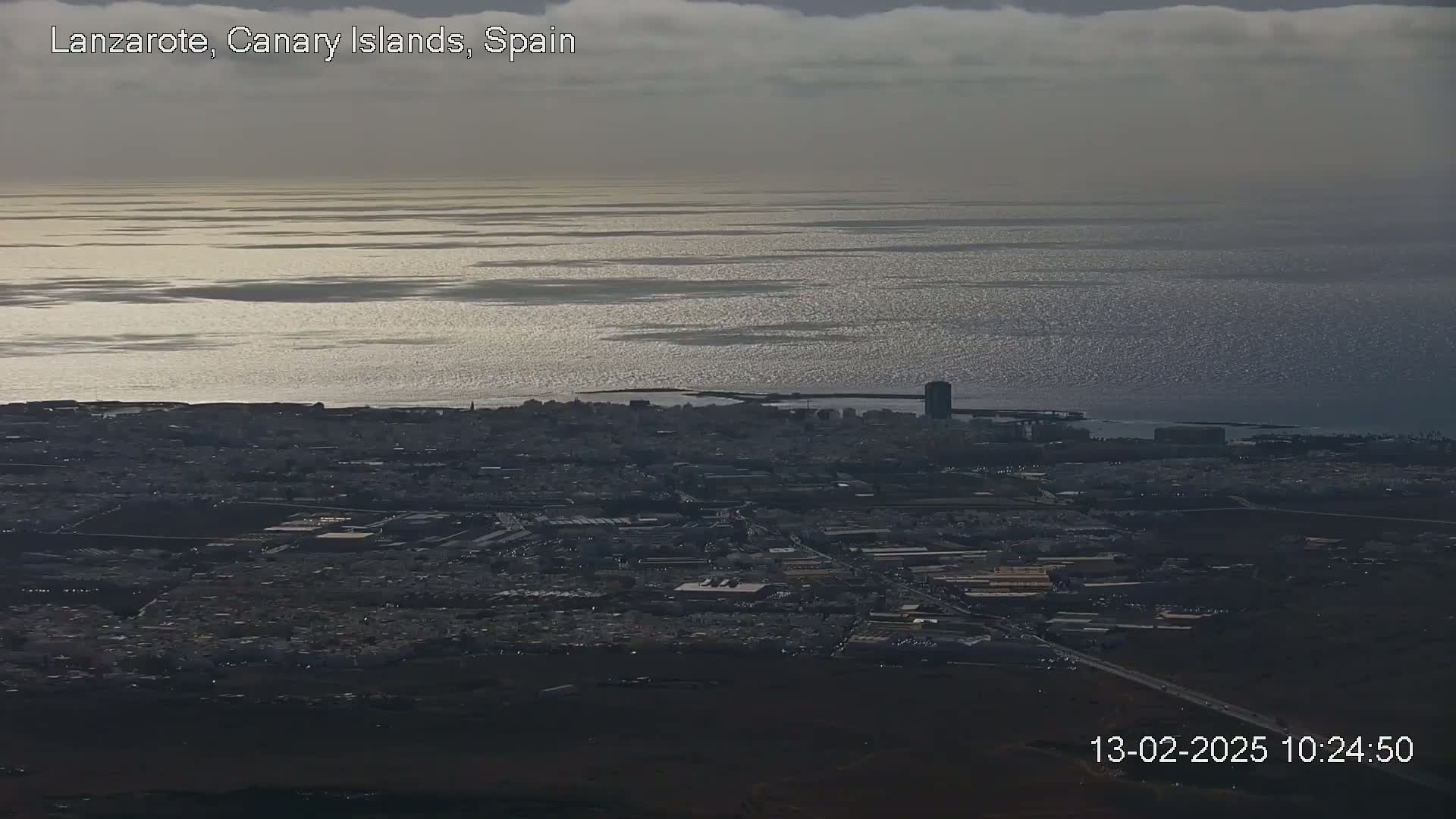 A coastal city with a dark, overcast sky and a shimmering ocean stretches to the horizon.