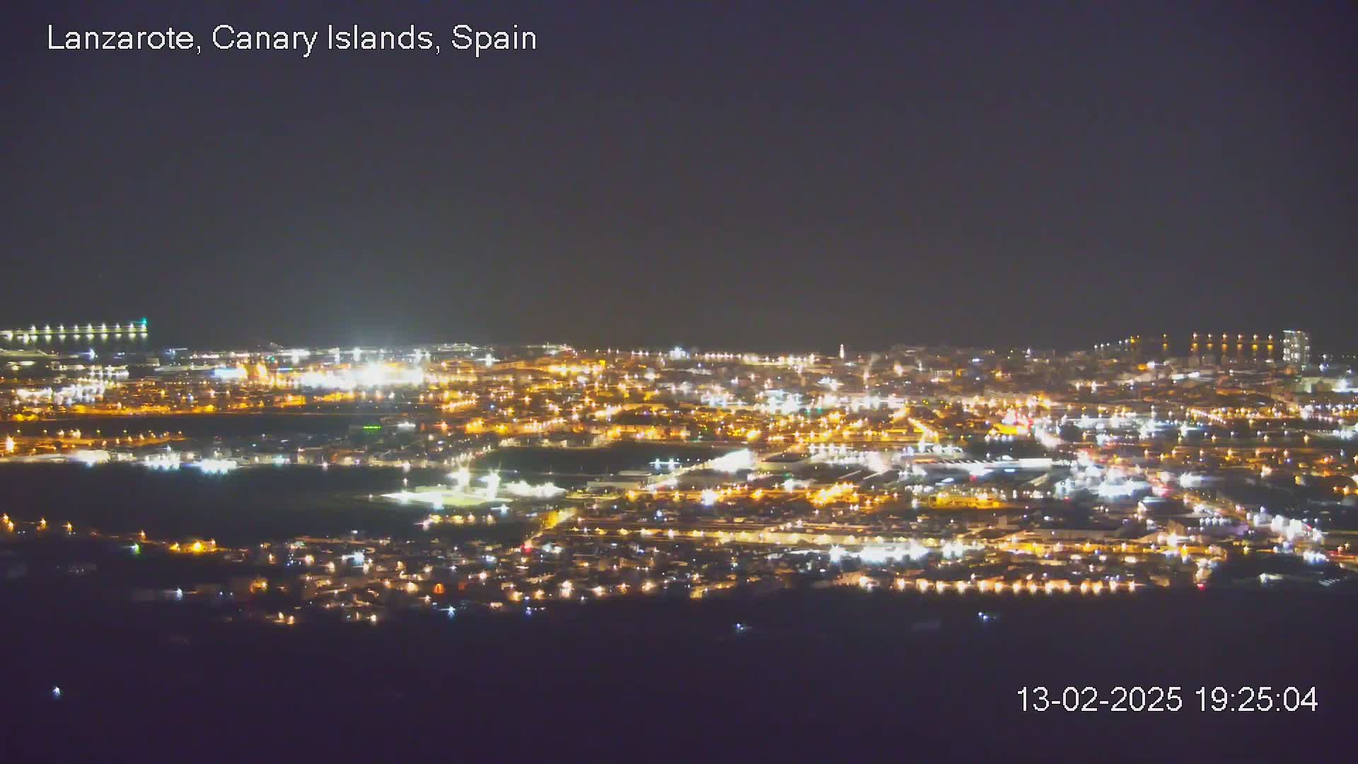 A nighttime, long shot of a city illuminated by many lights, under a dark sky.