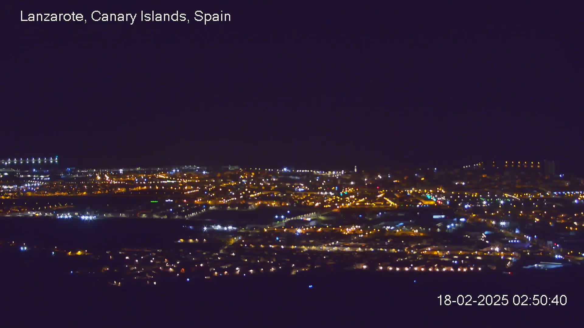 A sprawling city at night, illuminated by numerous lights under a clear, dark sky.
