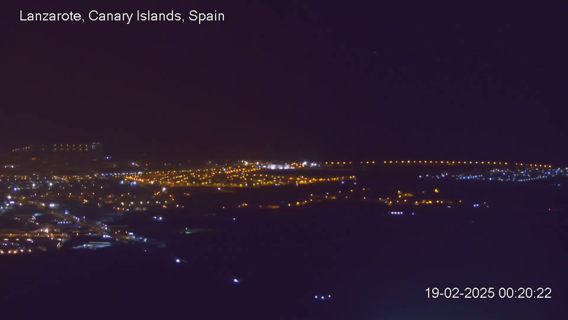 A nighttime view of a city illuminated by numerous lights under a clear, dark sky.