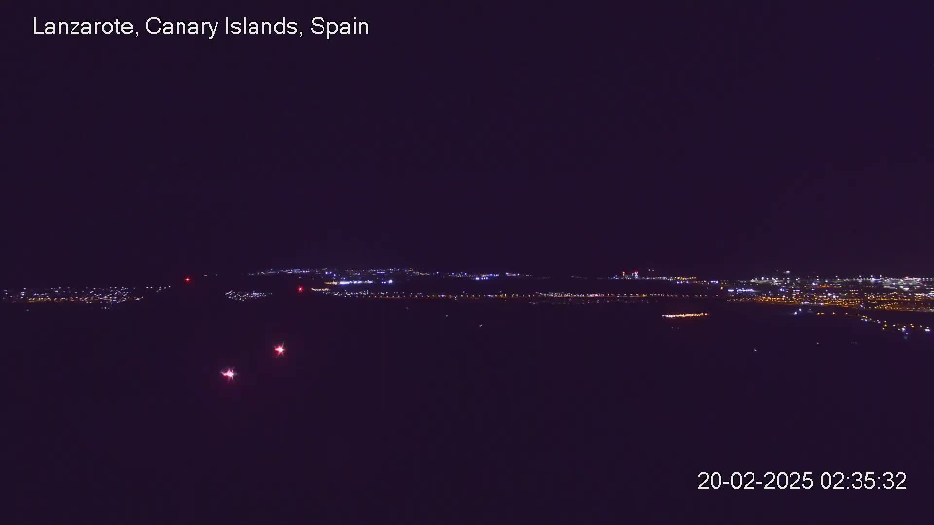 A distant city skyline is illuminated at night under a clear, dark sky.