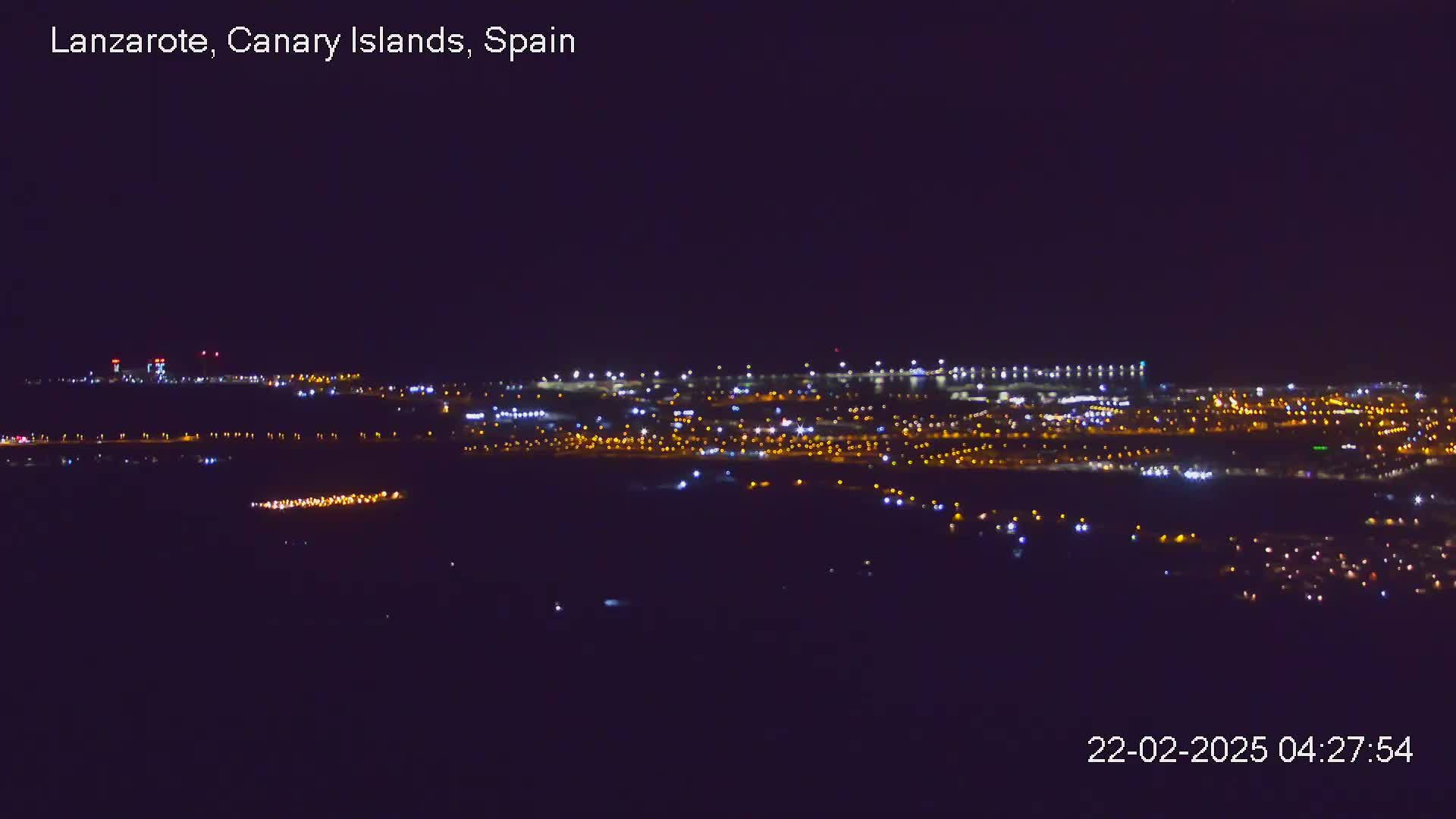 A nighttime, long-distance view of a city illuminated by numerous lights under a clear, dark sky.