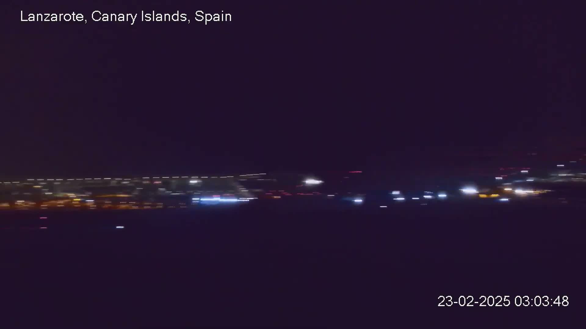 A distant line of city lights is visible at night under a dark sky.