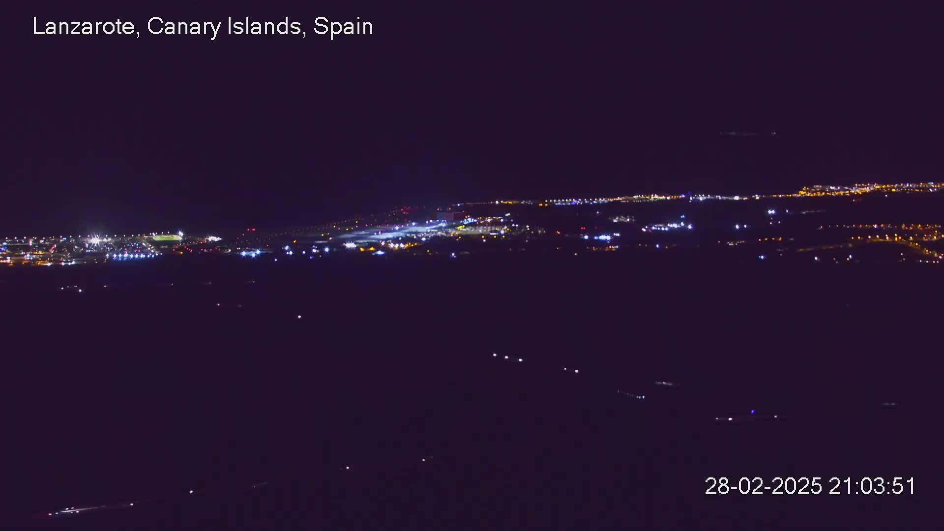 A nighttime, long-range view of an illuminated airport and surrounding area.
