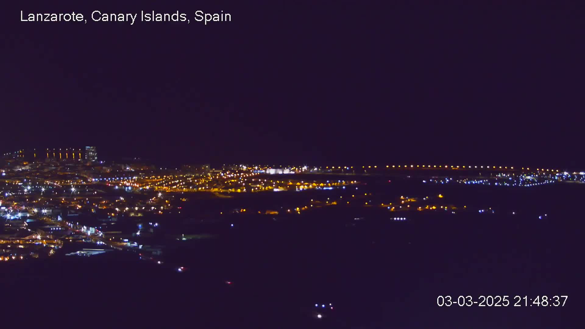 A nighttime, long-range view shows a city illuminated by numerous lights.