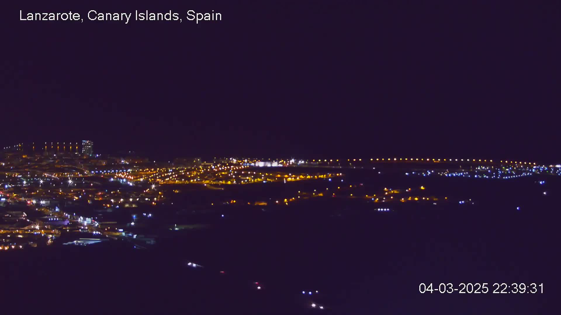 A nighttime, long-range view of a city illuminated by numerous lights under a clear, dark sky.
