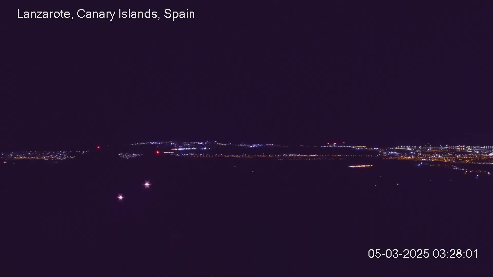 A distant city skyline illuminated at night under a clear, dark sky.