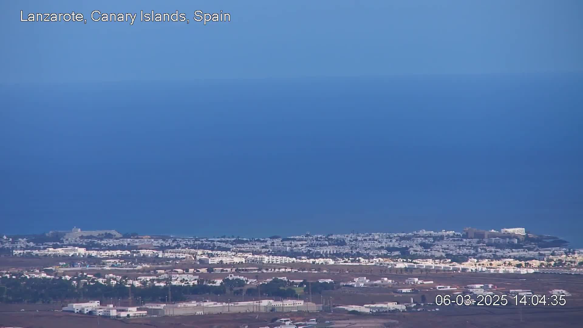 A sprawling, low-rise residential area near the ocean under a clear, blue sky.