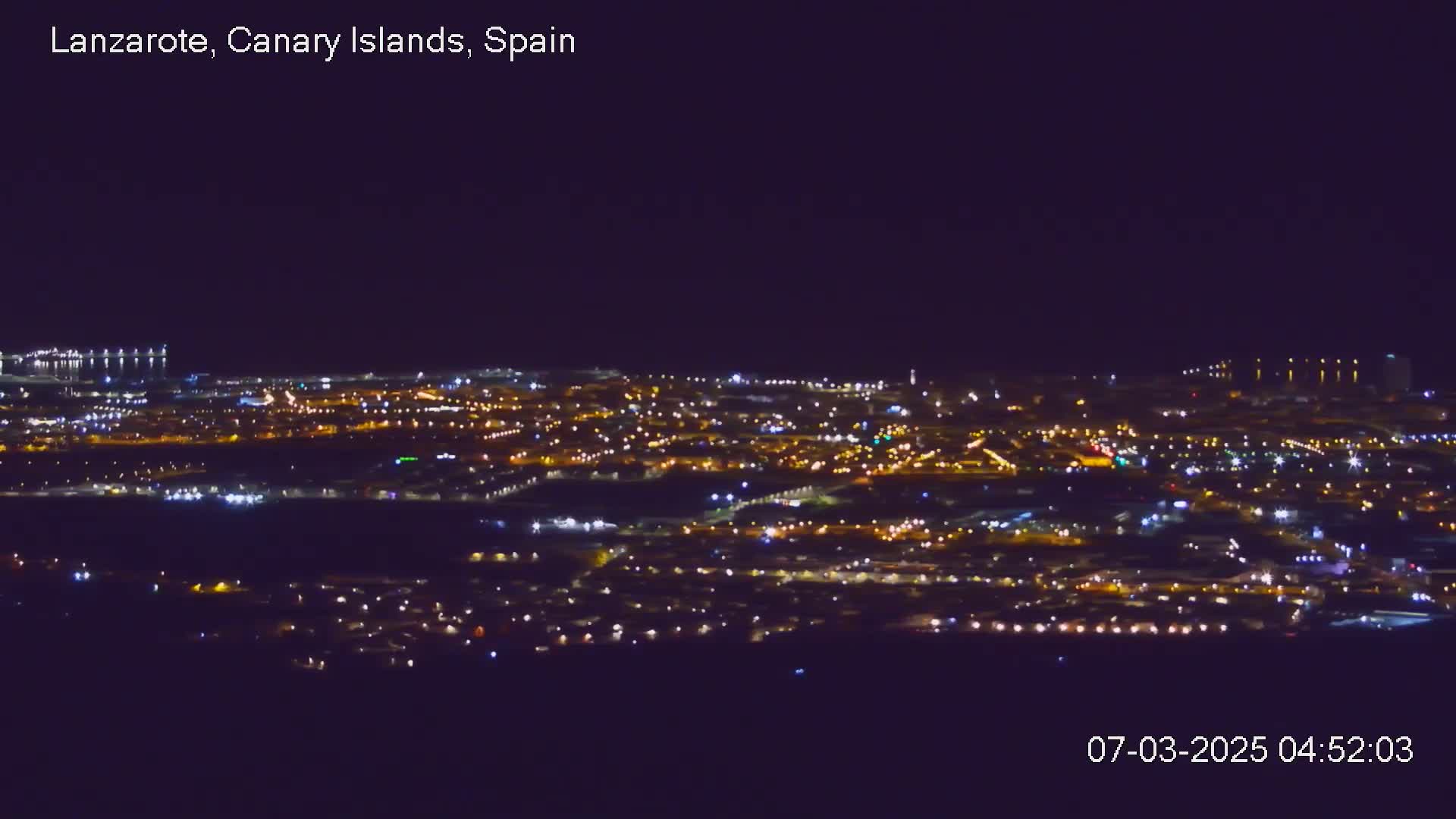 A nighttime, long-range view of a city illuminated by numerous lights.