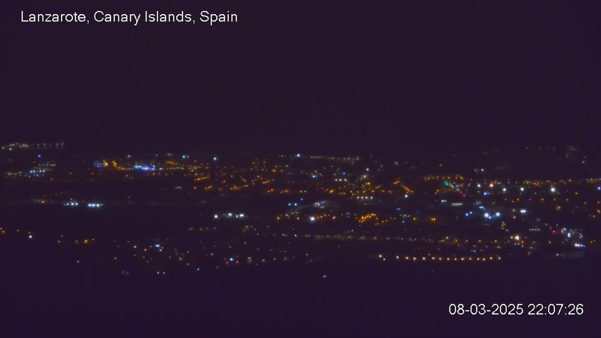 A nighttime, long-range view of a city illuminated by numerous small, scattered lights.