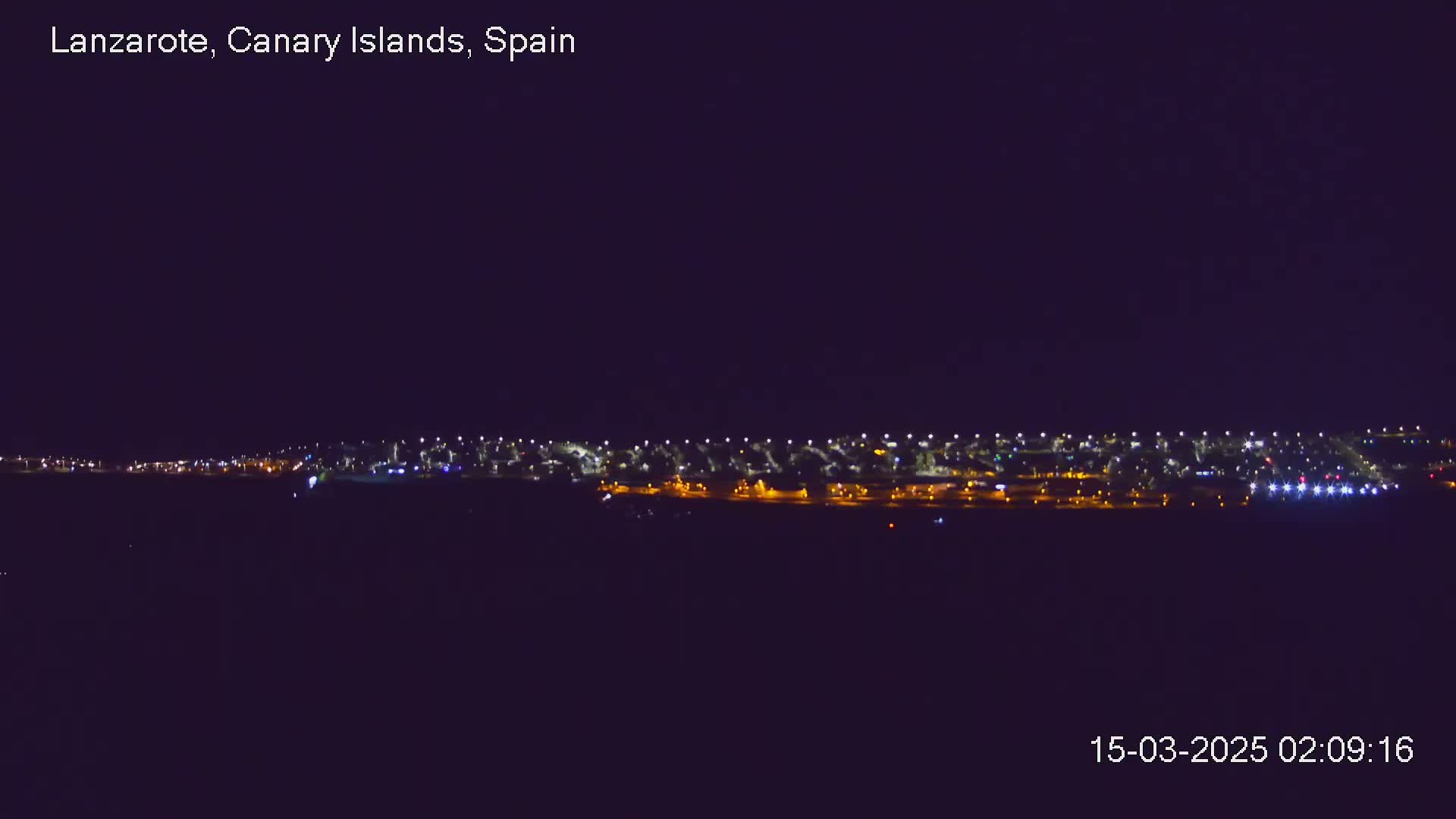 A long line of city lights is visible at night under a clear, dark sky.
