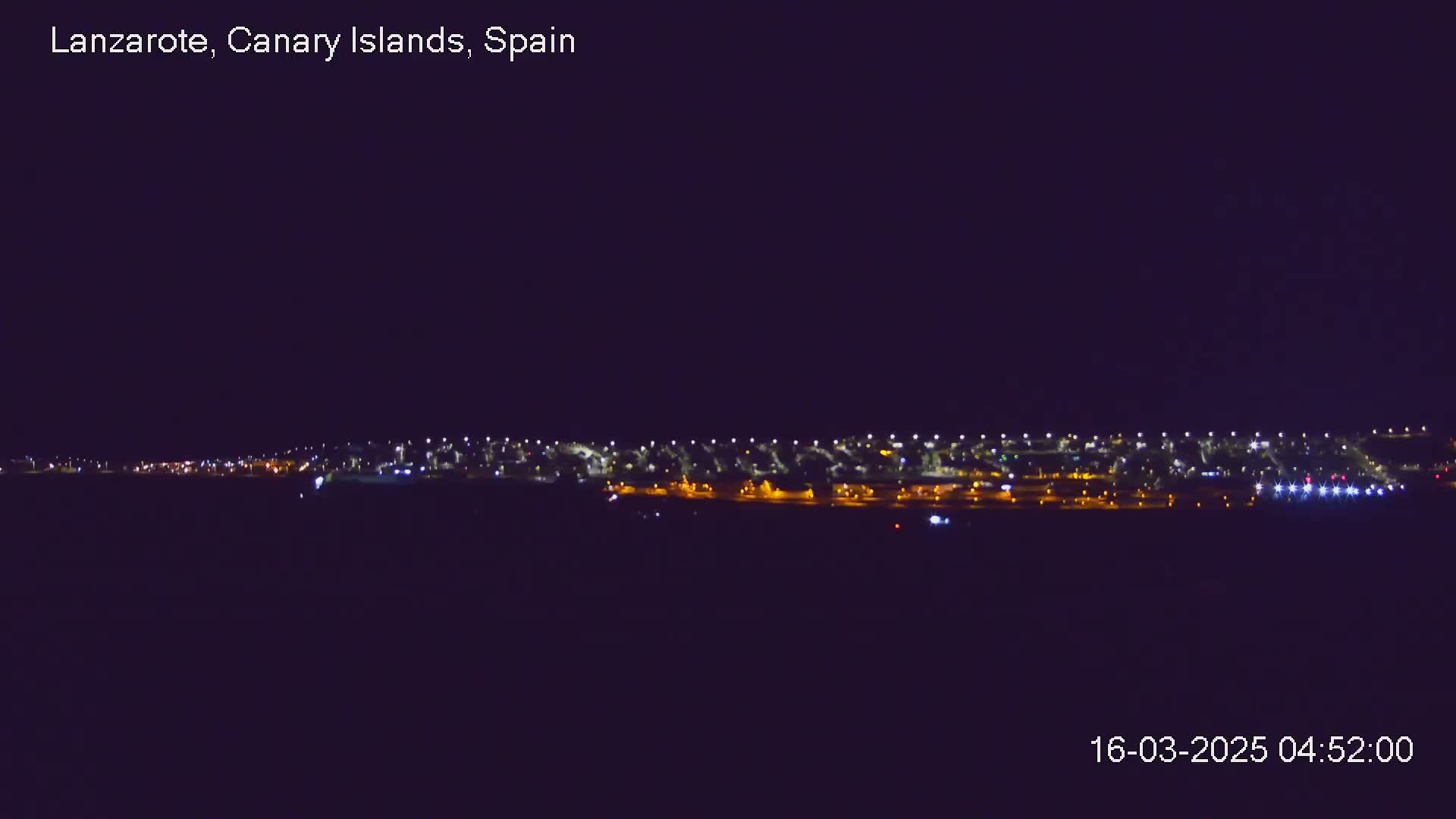 A nighttime long shot shows a line of city lights on a dark, clear night.