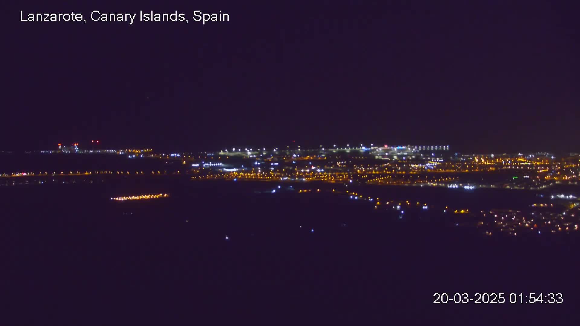 A distant city illuminated at night under a clear, dark sky.