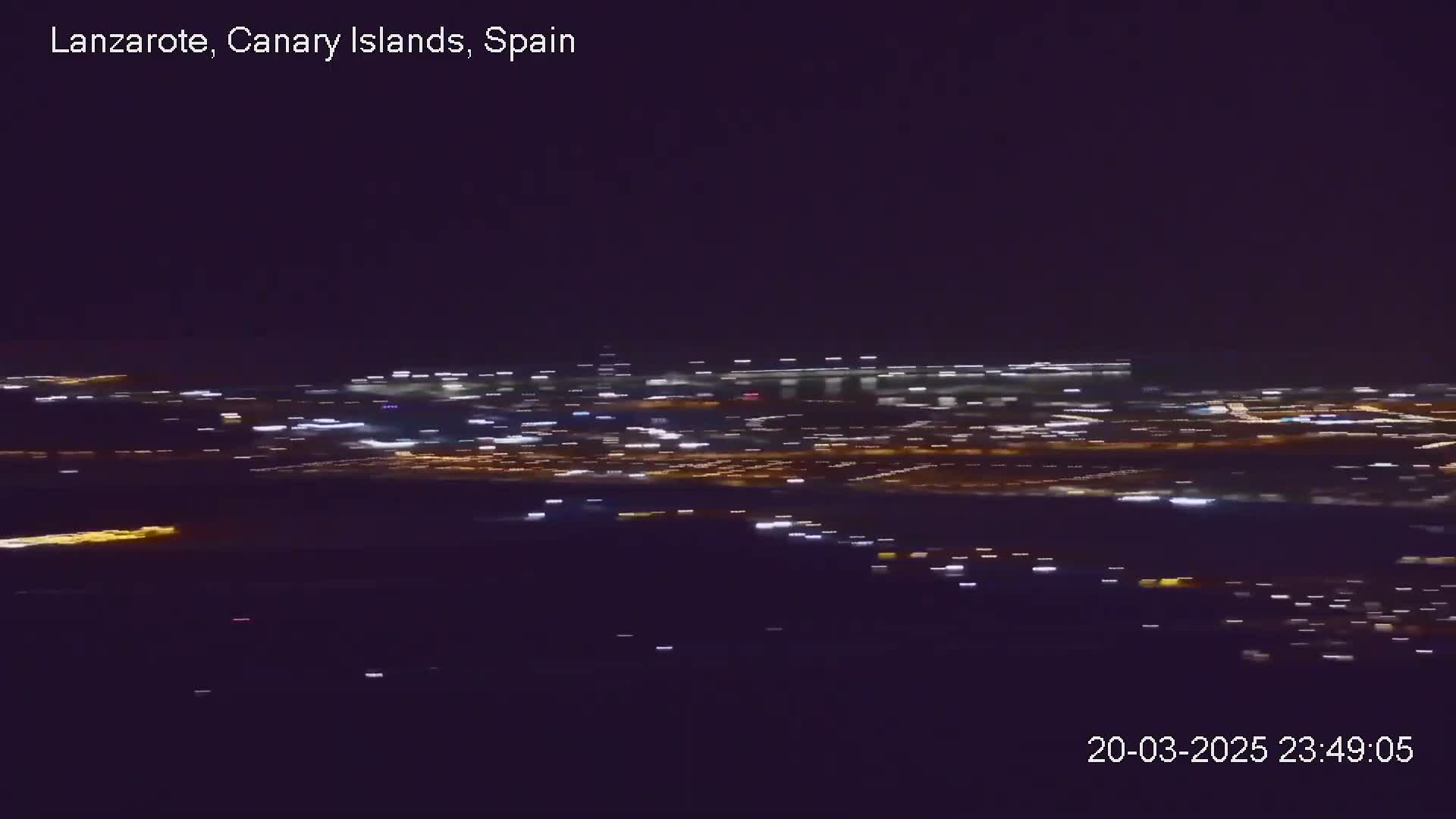 A nighttime, long-distance view of a city's lights spread across a dark landscape.