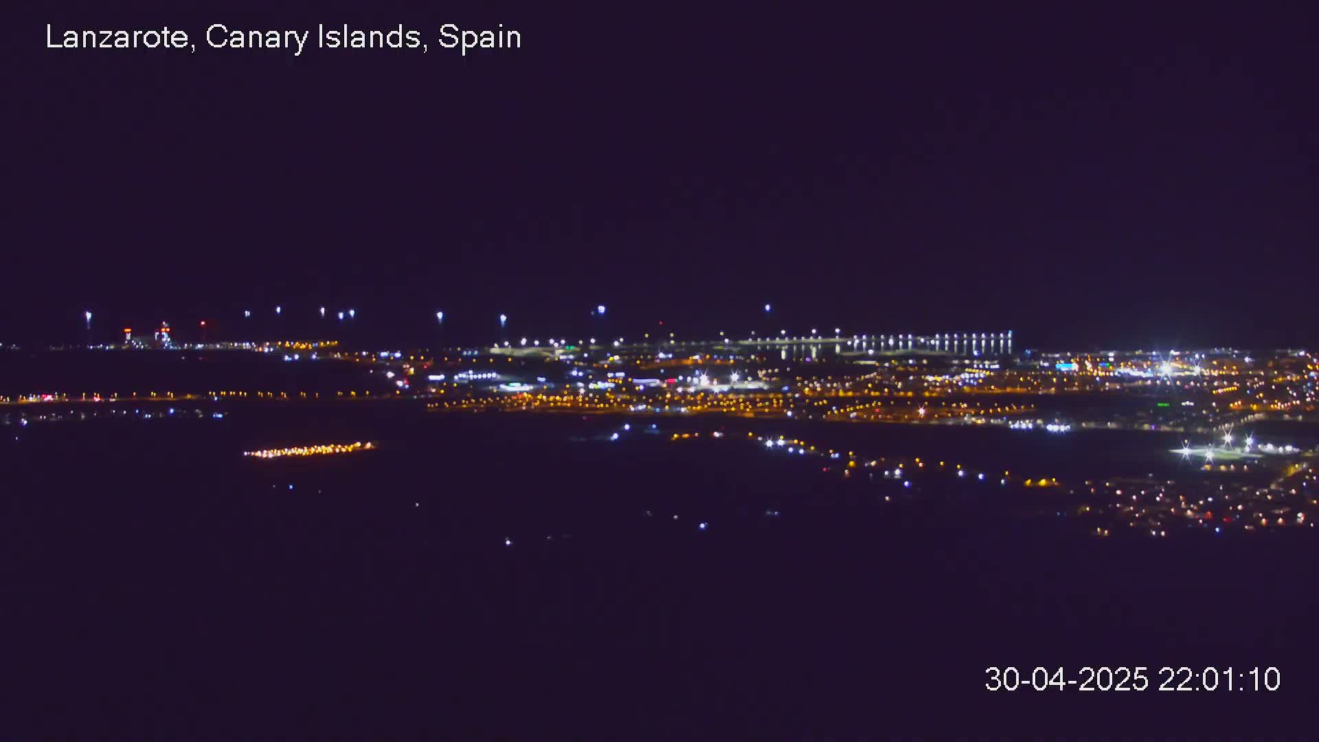 A nighttime, long-range view of a city illuminated by numerous lights.