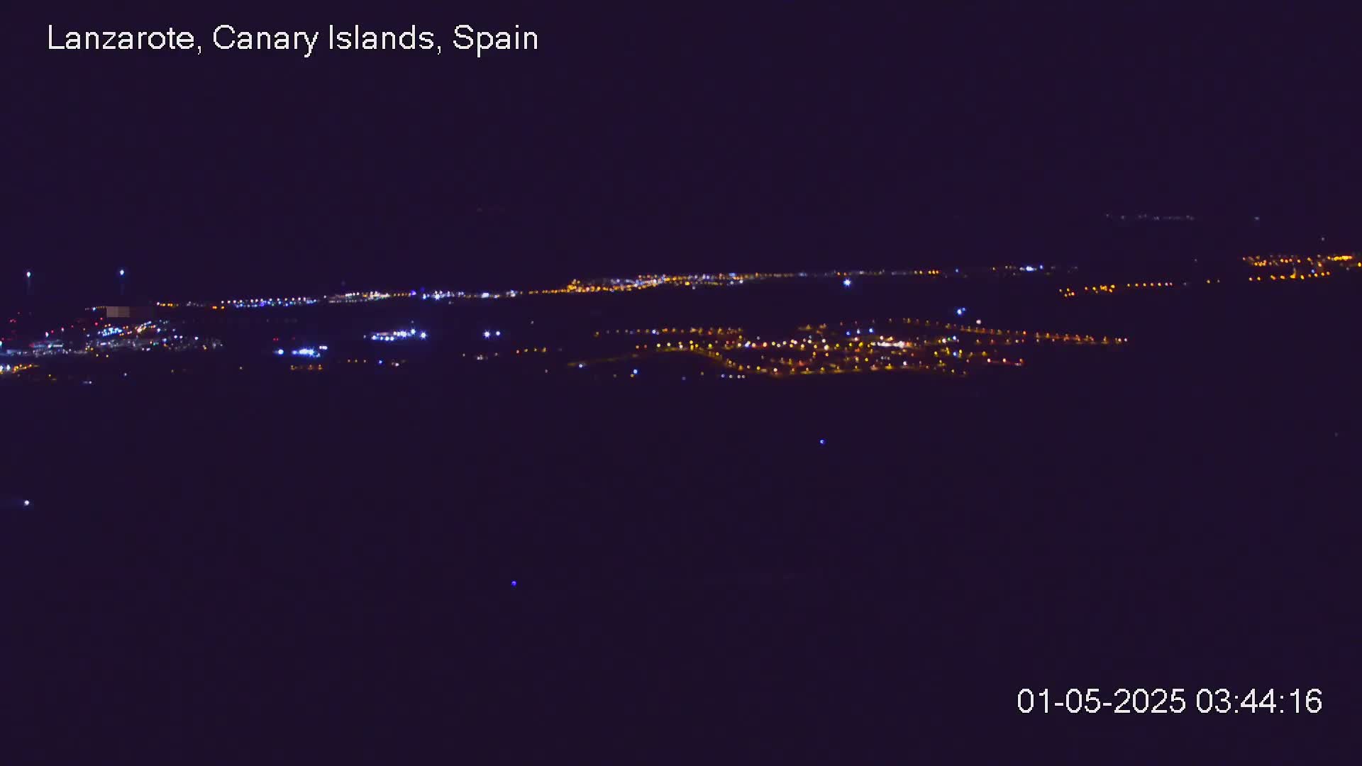 A nighttime long shot shows a sprawling city illuminated by scattered lights under a clear, dark sky.