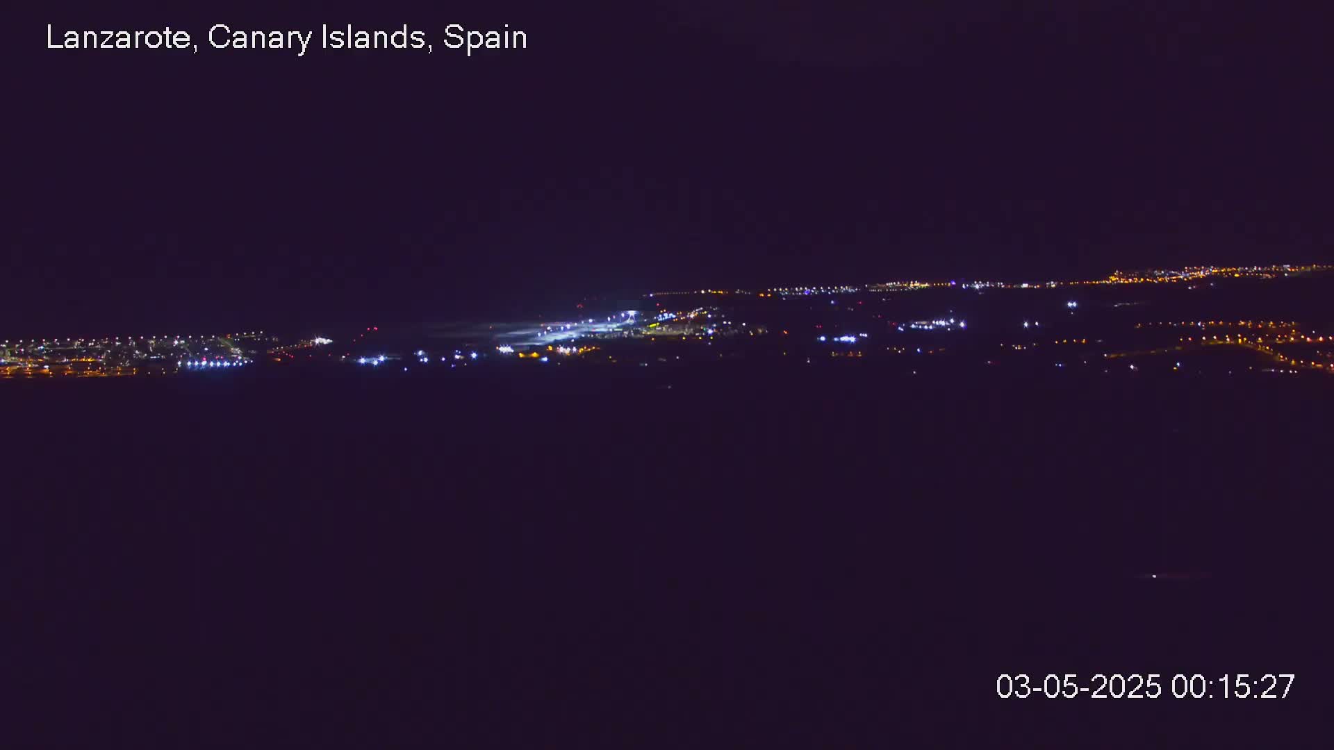 A distant, nighttime view of a city illuminated by numerous lights under a clear, dark sky.