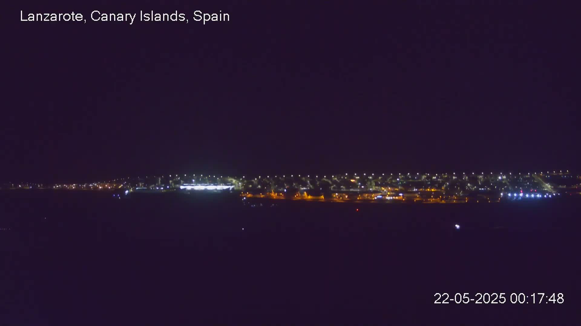 A long line of city lights is visible at night under a clear, dark sky.