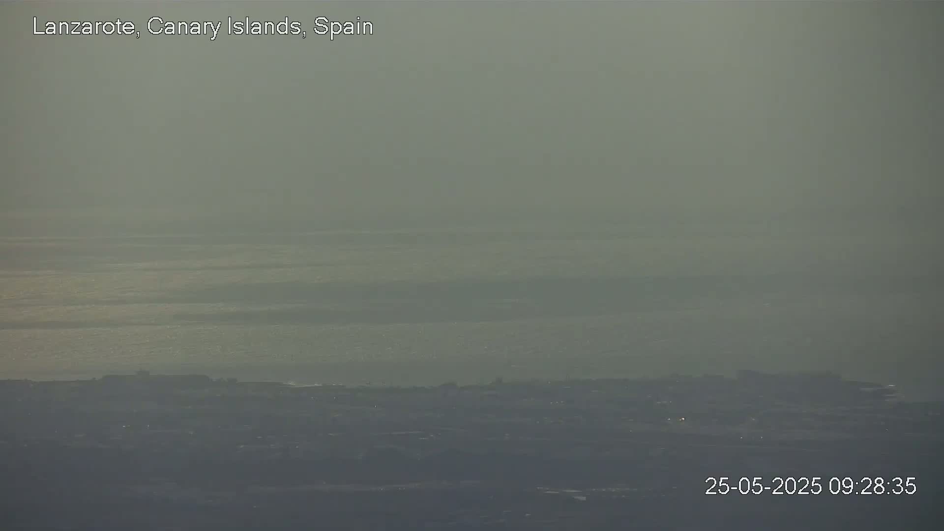 A hazy view shows a distant coastline and a body of water under a muted sky.