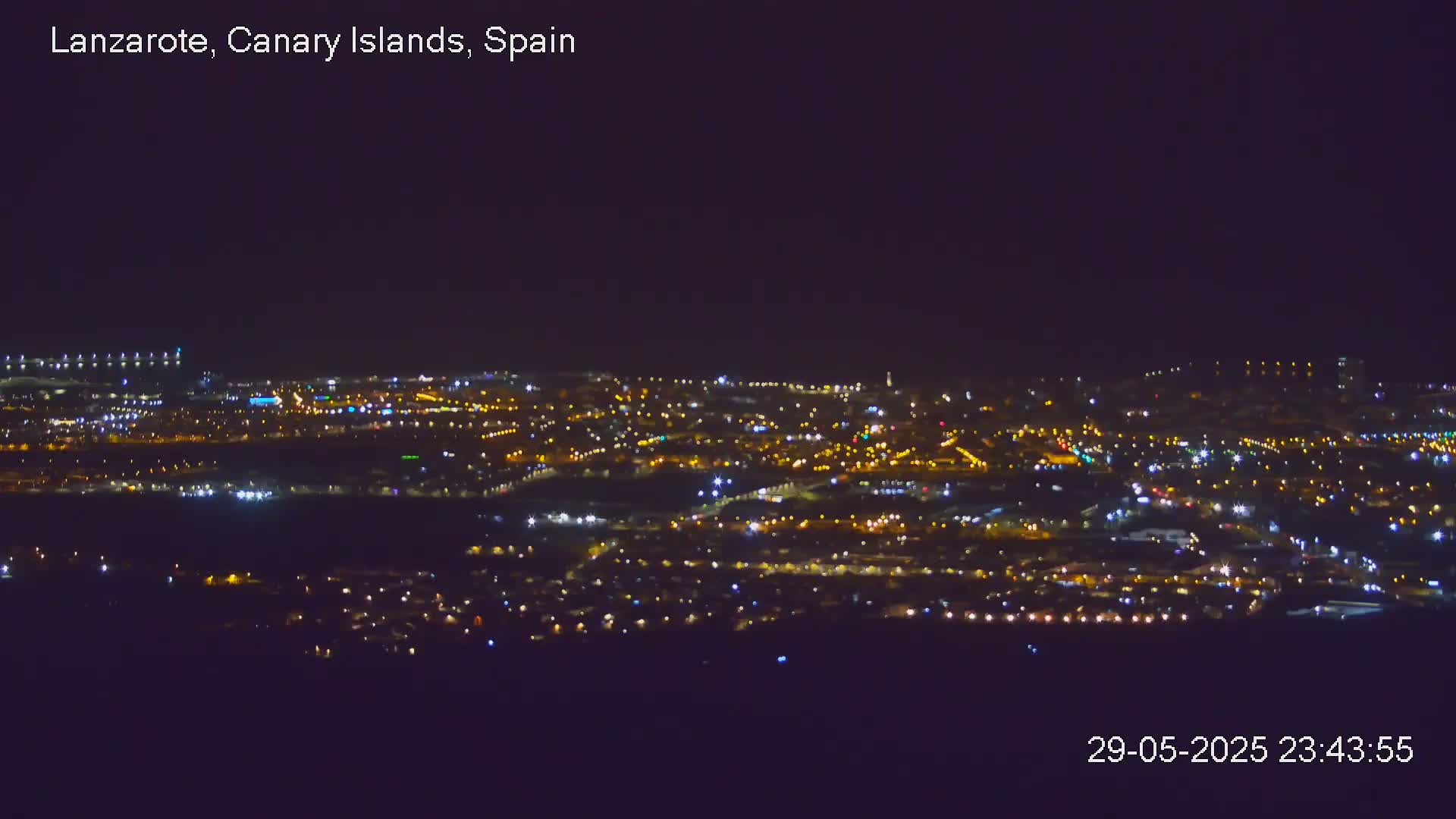 A nighttime, long-distance view of a city illuminated by numerous lights under a clear, dark sky.
