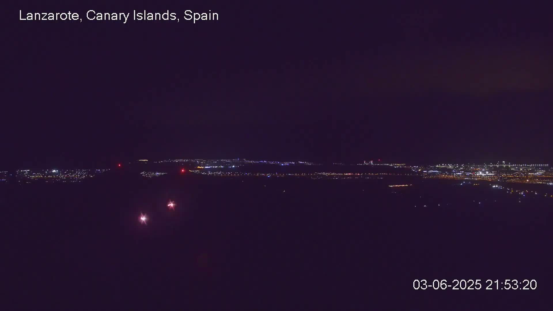 A nighttime long shot shows a distant city glowing with lights under a clear, dark sky.