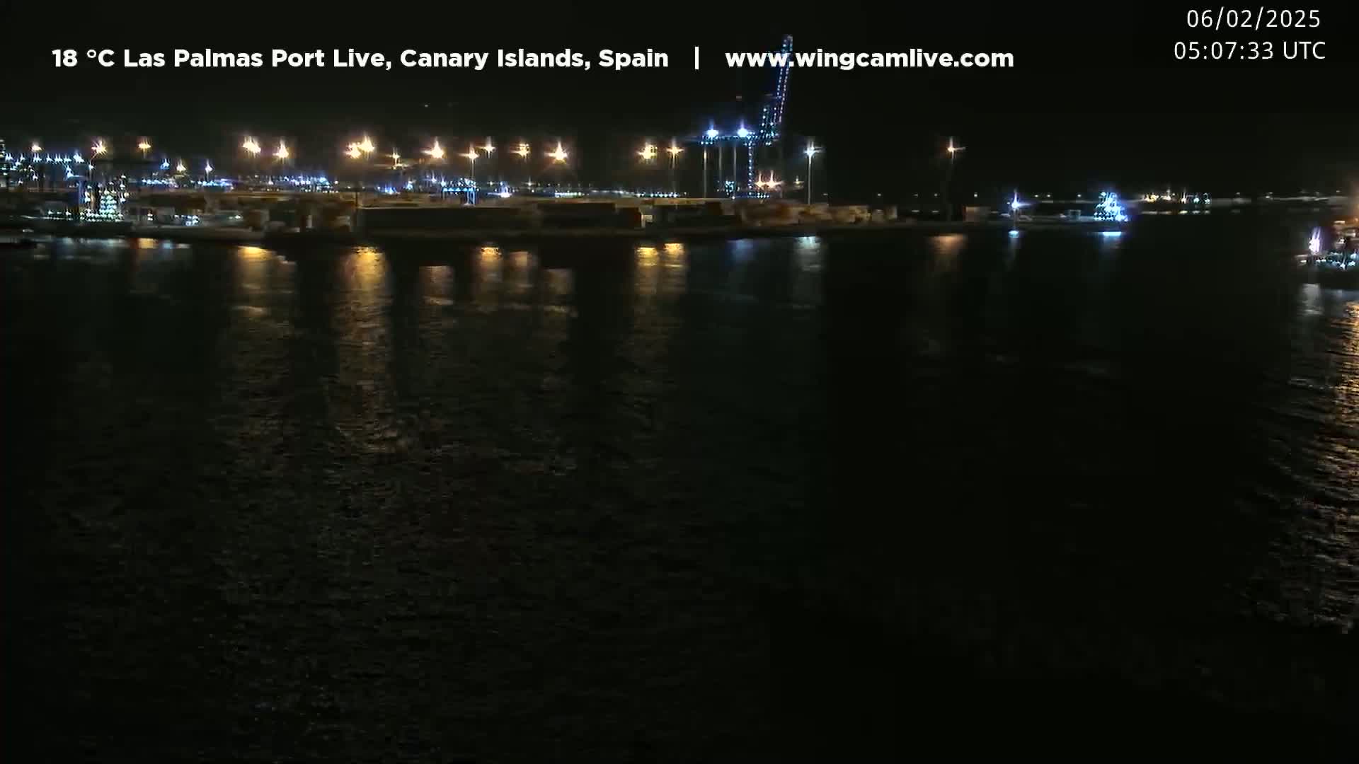 A nighttime view of a brightly lit port reflecting on dark water.