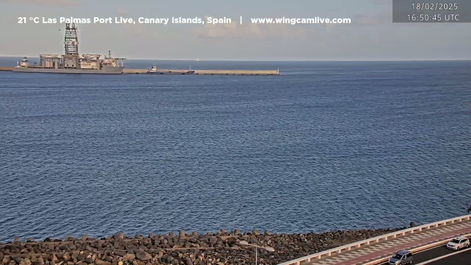 A large ship is docked at a port on a calm, clear day.