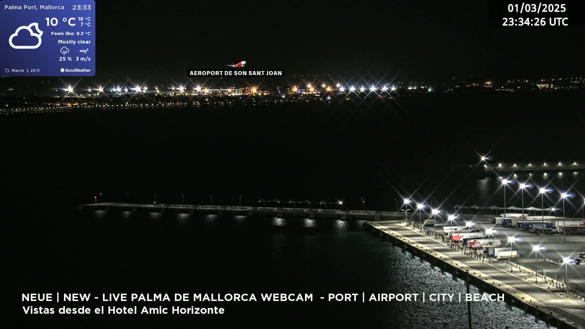 A nighttime long shot of a brightly lit port and airport across the water, under mostly clear skies.