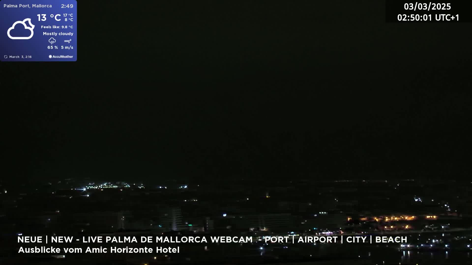 A mostly cloudy night scene shows a distant city illuminated with lights under a dark sky.