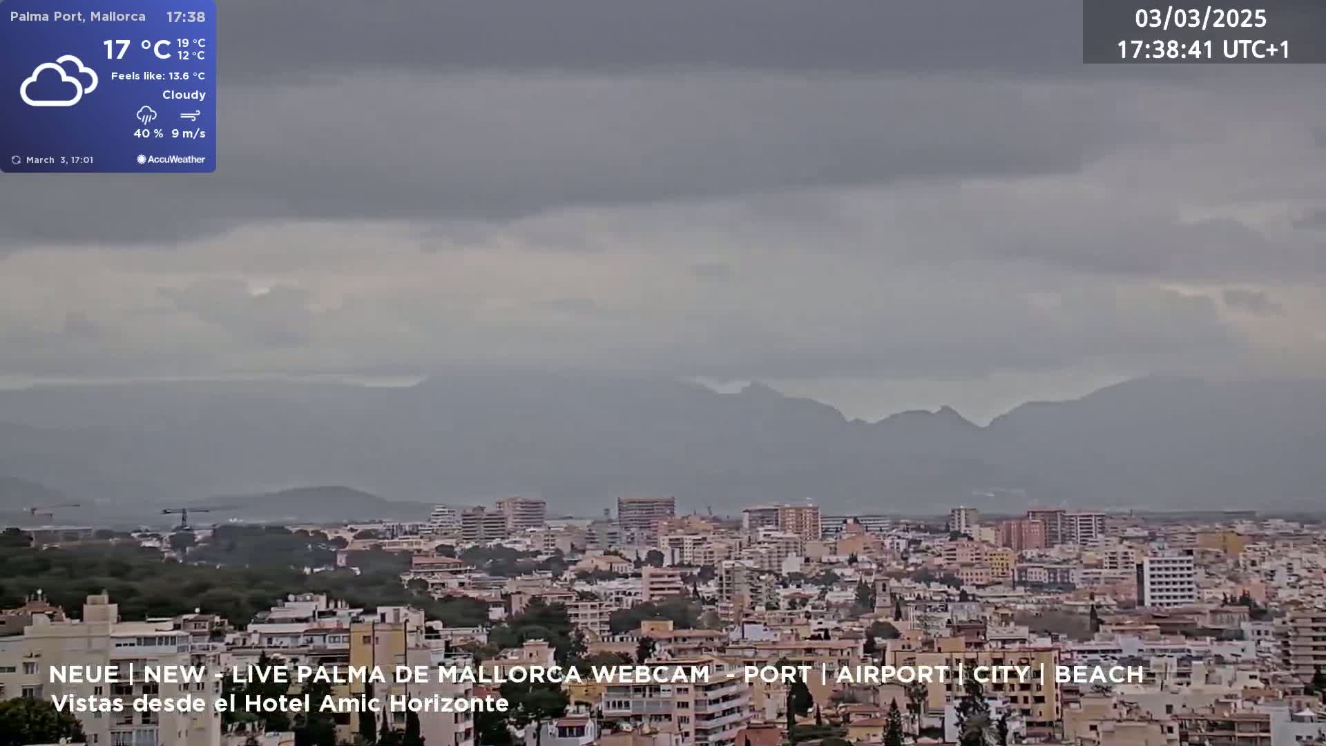 A cloudy cityscape with mountains in the background under overcast skies.