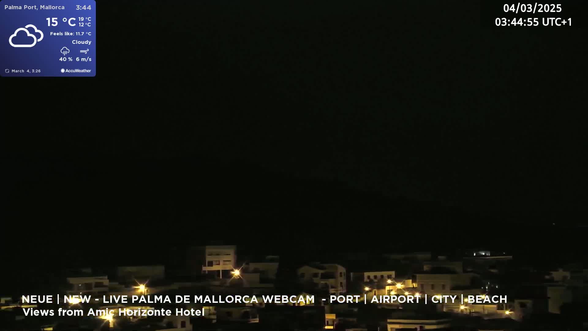 A nighttime view of a town with scattered lights under a cloudy sky.