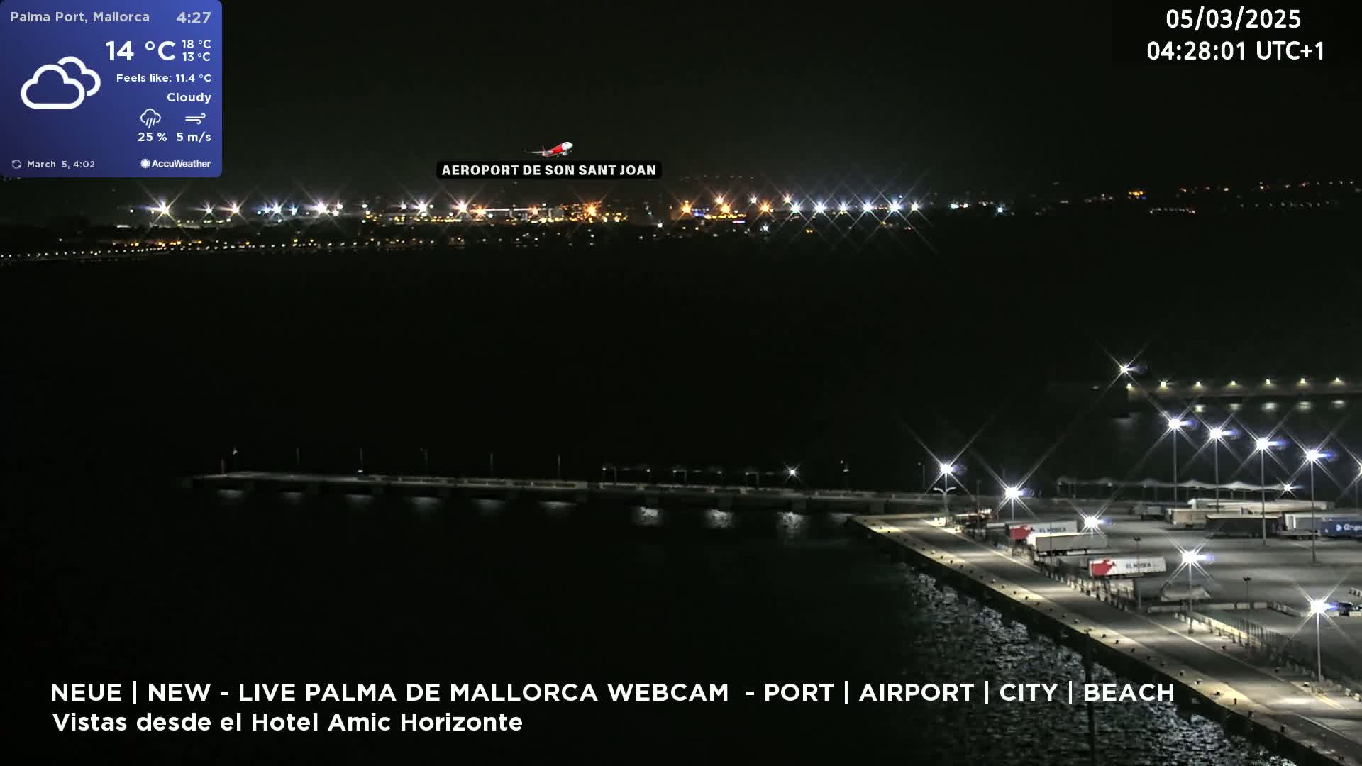 A nighttime, cloudy view of a brightly lit port and airport across a body of water.