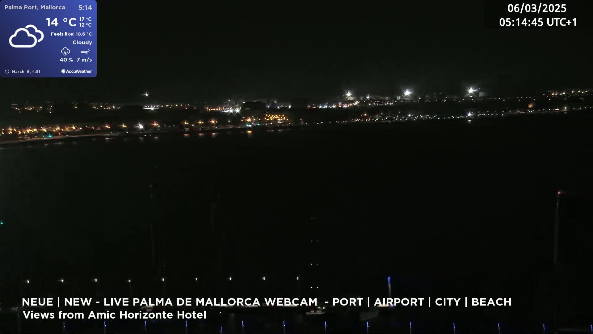 A nighttime, cloudy view of a city's illuminated waterfront under a dark sky with a gentle breeze.