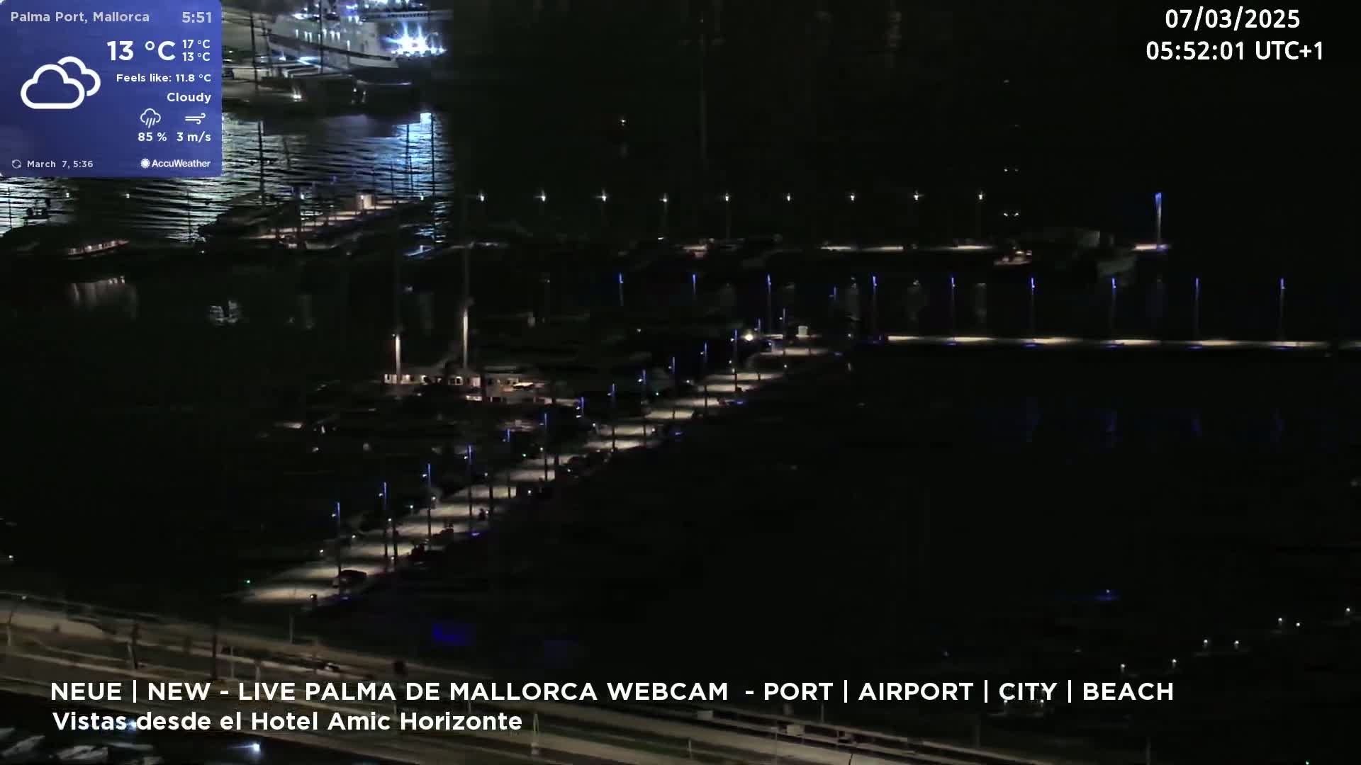 A nighttime, cloudy view of a marina filled with boats, illuminated by lights along a pier.