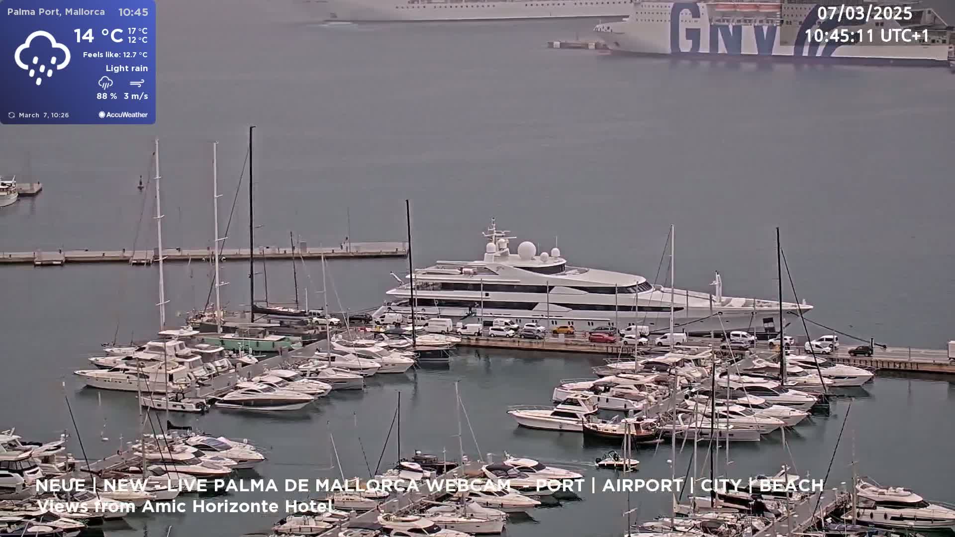 A large marina filled with yachts and sailboats under light rain.