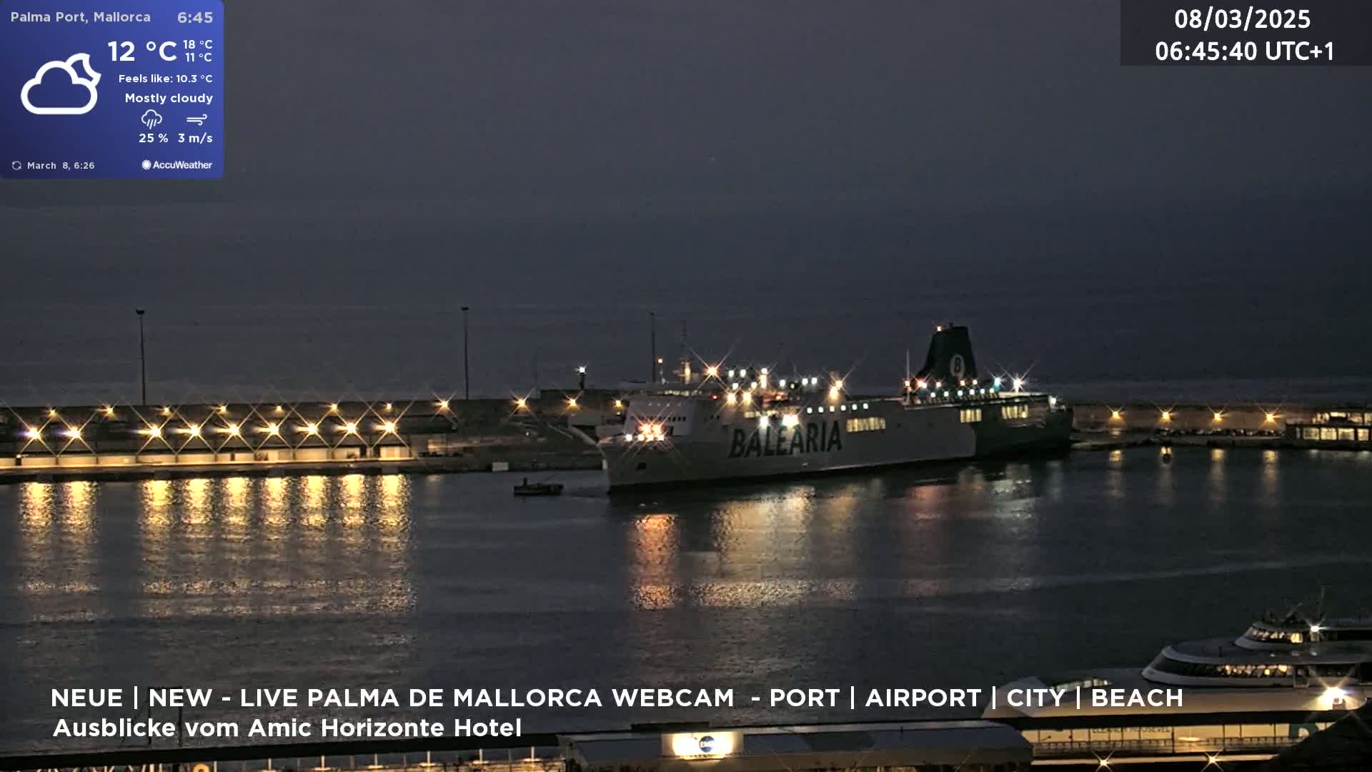A large ferry is docked at a nighttime port under mostly cloudy skies.
