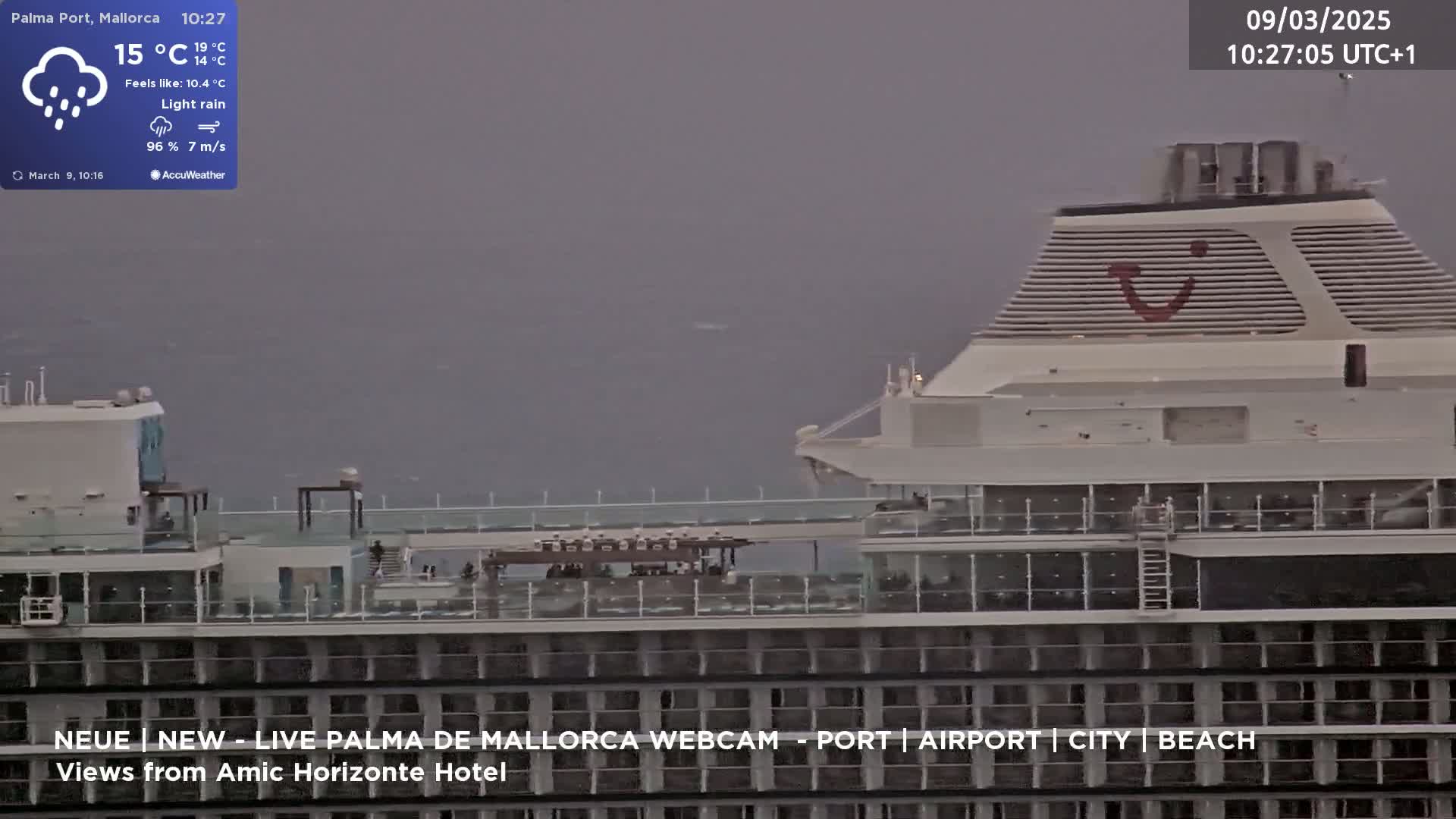 A large cruise ship is visible at sea during light rain and overcast conditions.