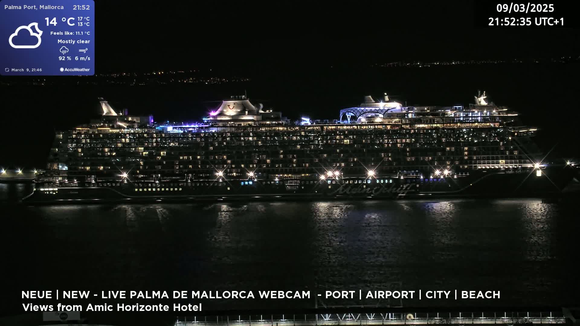 A large cruise ship is docked at a port at night under mostly clear skies.