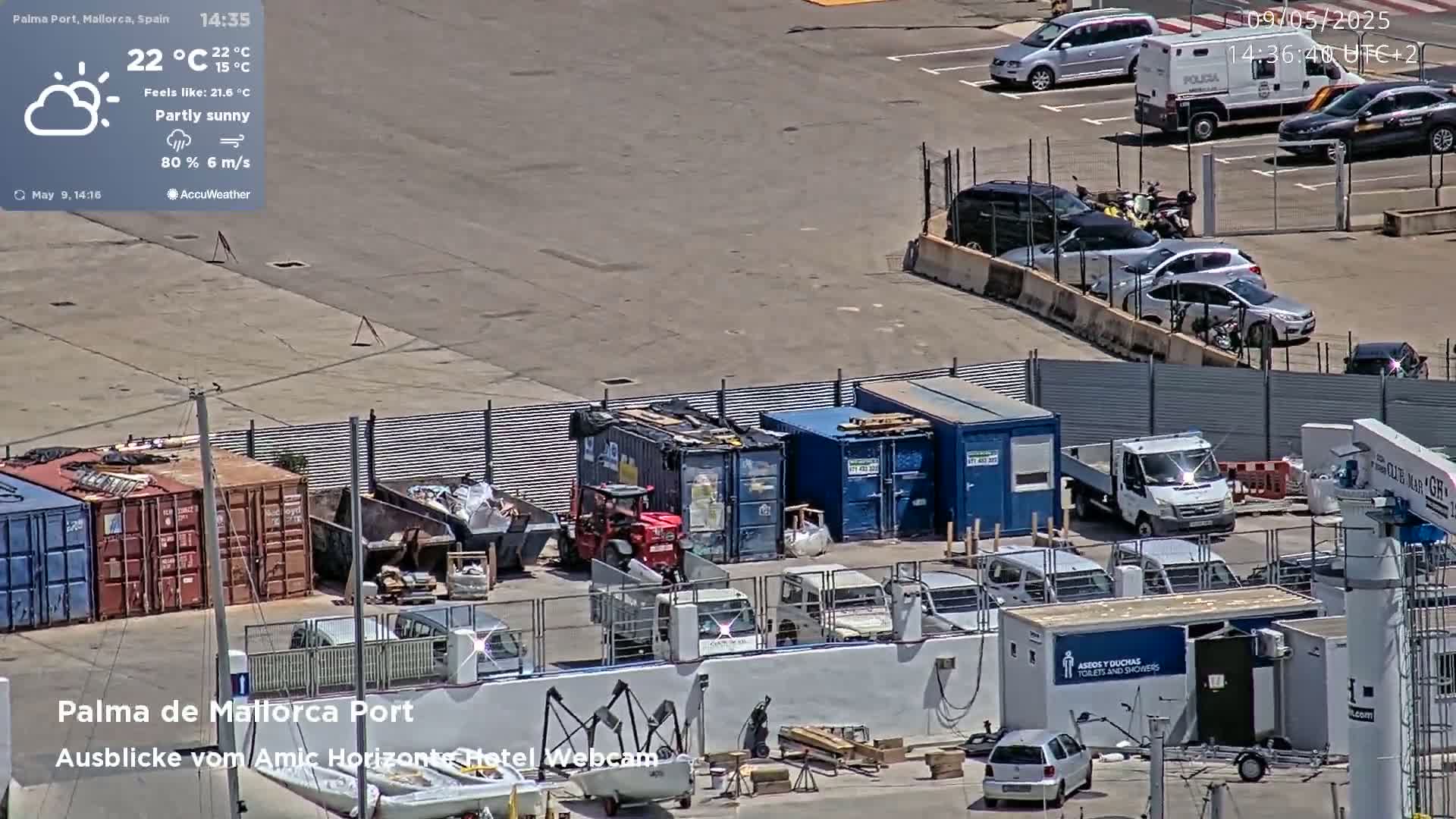 A partly sunny port area with numerous cars, shipping containers, and construction equipment.